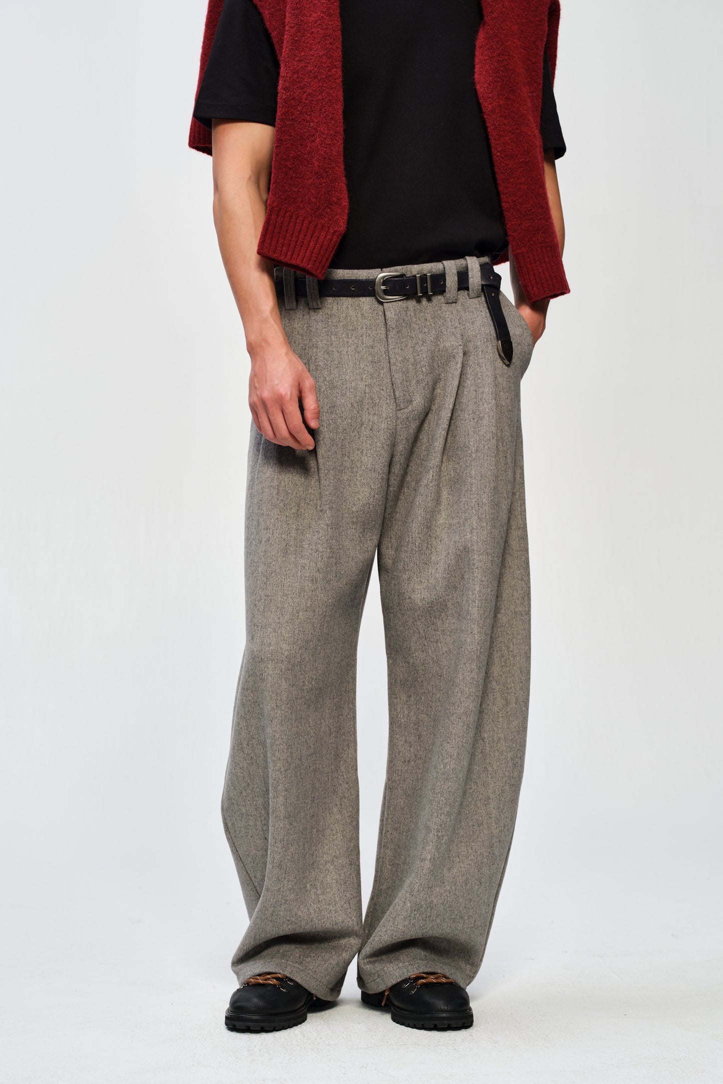 Person wearing gray wide-leg pants with a red vest and black shirt on a white background